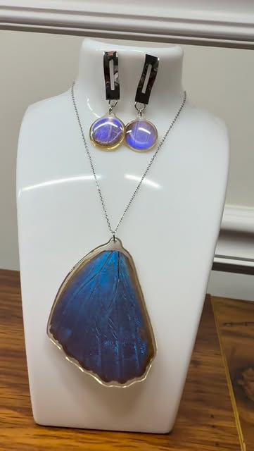 Blue butterfly wing pendant displayed with matching earrings